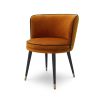 A luxurious orange velvet dining chair with a swivel seat, black legs and gold capped feet 