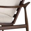 A stylish accent chair by Eichholtz with a brown finished frame and beautiful boucle cream upholstery 