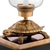 a little tortoise atop a granite base carrying a candle encased in glass atop its back