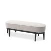 Grey boucle upholstered bench with gentle curves and three black tapered legs on either side