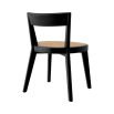 A rattan base dining chair with tapered legs and black frame