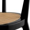 A rattan base dining chair with tapered legs and black frame