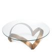 Curvaceous trio-legged coffee table in brass with round glass top