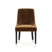 A timelessly elegant dining chair upholstered in velvet with black legs and golden caps. Pictured in Vienna Teja.