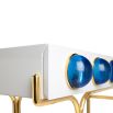 A futuristic white console table with blue acrylic cabochons and a polished brass base 