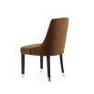 A timelessly elegant dining chair upholstered in velvet with black legs and golden caps. Pictured in Vienna Teja.