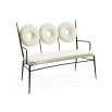 A dining bench upholstered in a boucle fabric. Placed on a blackened steel frame and polished brass sphere decorations.