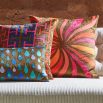 Firey design velvet cushion with warm tones on a brown background