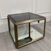 A contemporary side table by Eichholtz with a brushed brass frame, smoked glass top and mirrored glass bottom shelf