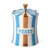 A glamorous candle by Jonathan Adler with a blue and brass finished peace vice canister