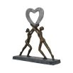 A beautiful, dark bronze sculpture of two figures holding up a heart which embodies love 