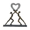 A beautiful, dark bronze sculpture of two figures holding up a heart which embodies love 
