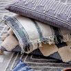 A cosy cushion with rows of thick string on a grey weaved cotton 