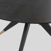 Dining table with statement base of slender spokes and brass caps
