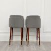 An elegantly glamorous bar chair with grey velvet upholstery and long lacquered legs with polished brass details 