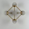 Elegant brass wall fixture with five frosted orb shades and geometric appeal