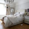Designer French style bed with a curved, button back headboard and studding