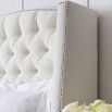 Designer French style bed with a curved, button back headboard and studding