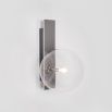 A chic polished nickel wall lamp with a transparent glass lampshade