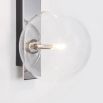 A chic polished nickel wall lamp with a transparent glass lampshade
