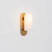 Natural brass finish wall lamp with a long translucent glass globe