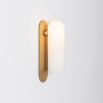 Contemporary solid brass wall lamp in a natural finish with a long translucent glass lampshade