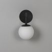 A luxury wall lamp by Schwung with a spherical glass shade mounted on a black gunmetal plate