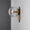A luxury wall sconce by Schwung with a brushed brass finish and a glamorous detailed clear glass bulb