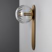 A glamorous wall lamp by Schwung with a brushed brass finish and detailed clear glass bulb