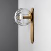 A stunning wall lamp by Schwung with a glamorous brushed brass finish and elegant detailed clear glass bulb