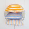 A colourful children's cushion with an orange and blue pattern and finished with white piping