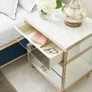 A luxury bedside table with a mirrored design, white marble top and glamorous gold detailing