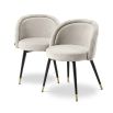 A decadent pair of sand-coloured, upholstered Eichholtz chairs that give a retro feel