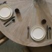 Striking round dining table with rustic bronze base and sunburst woodgrain surface