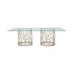 A luxury coral-inspired dining table with silver golden tones and a clear glass top 