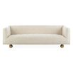 A stylish sofa by Jonathan Adler with a luxury cream upholstery and glamorous gold orb feet