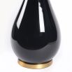 A luxurious black lacquered side lamp with a linen lampshade and brass details