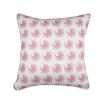 A white cushion with matching piping and a pink palm-like pattern