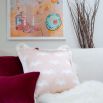 A delicate pastel pink cushion with a white pattern and elegant fringe