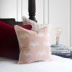 A cute pastel pink cushion with white piping and leaf-like design