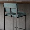 A chic, modern bar stool with a minimal black metal frame and velvet upholstery 