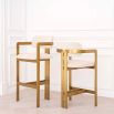A luxury bar stool by Eichholtz with a boucle seat and brushed brass legs