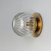 A luxury wall sconce by Schwung with a glamorous brass finish and elegant detailed clear glass bulb