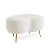 A chic, kidney-shaped shearling ottoman with polished brass legs 