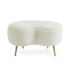 A chic, kidney-shaped shearling ottoman with polished brass legs 