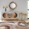 The Chambeige Bar Cart features back-painted glass shelves in a captivating Chambeige hue, framed by polished brass for a glamorous touch.