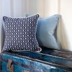 An art deco inspired square cushion with white floral motifs on a dark blue background