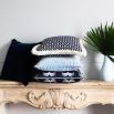 An art deco inspired square cushion with white floral motifs on a dark blue background