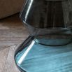 Glass-based side table with sculptural silhouette and round marble top