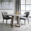 A stylish round and richly grained oak veneer dining table by Uttermost with an elm wood trestle base